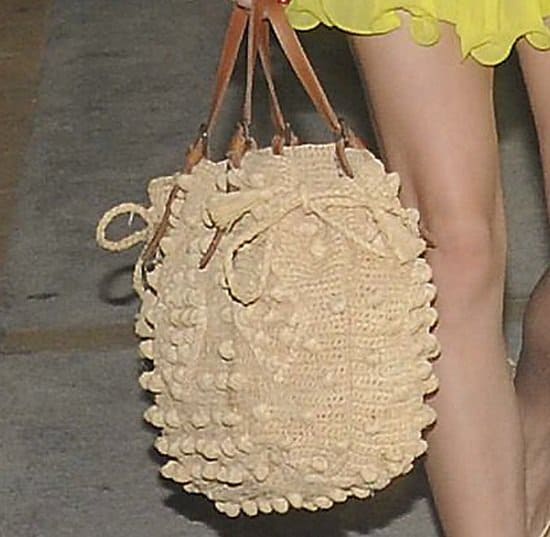 Olivia Palermo totes a handknitted purse with pom-pom balls