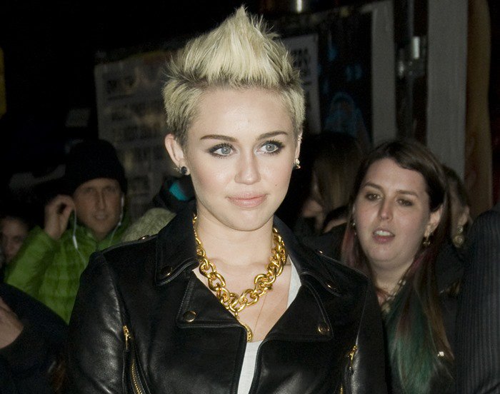 Miley Cyrus wears a statement necklace and a black Moschino Cheap & Chic leather jacket