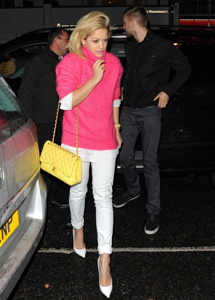 Rita in a pink sweater, white jeans, and a chic yellow Chanel bag