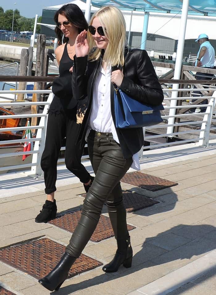 Dakota Fanning a dark-hued ensemble consisting of a white polo shirt, green leather pants from Current / Elliott, black booties, and a black leather jacket