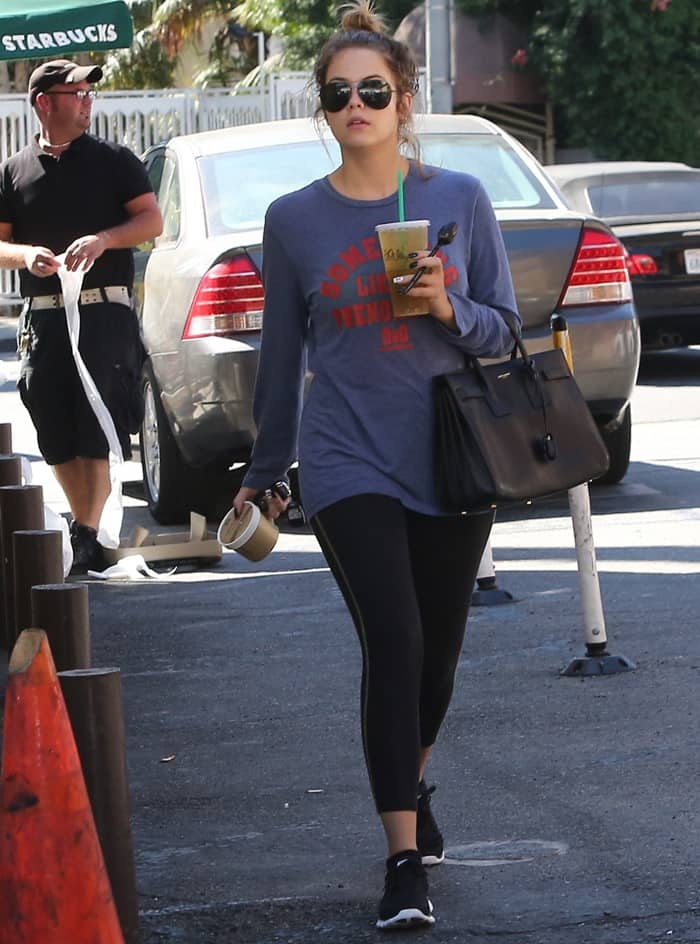 Ashley Benson dressed down in a gray printed sweater, black leggings, and sneakers