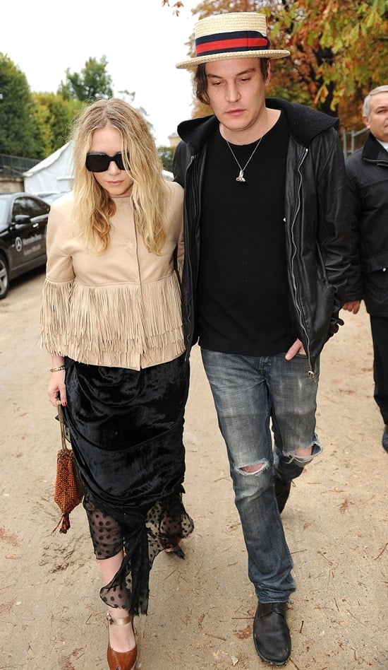 Mary-Kate Olsen (pictured with Nate Lowman) attends Paris Fashion Week S/S 2010 in a fringe jacket while carrying a beaded fringe wristlet on October 10, 2009