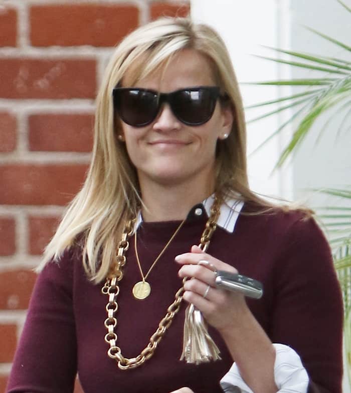 Accessorizing with gold jewelry, Reese Witherspoon rocked a sweater over a button-down shirt