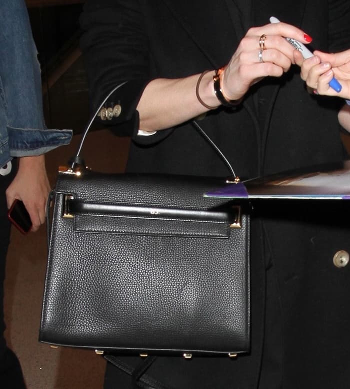 Dakota Johnson shows off her Cartier Juste Un Clou ring and black Valentino My Rockstud bag