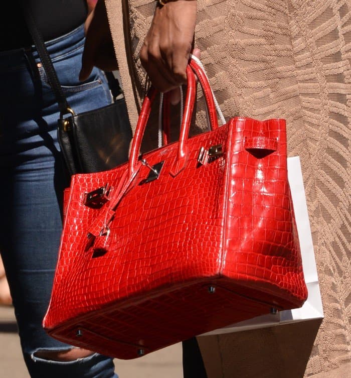 EJ Johnson carrying a fiery red Hermes Crocodile Birkin, which has a price tag of about $100,000