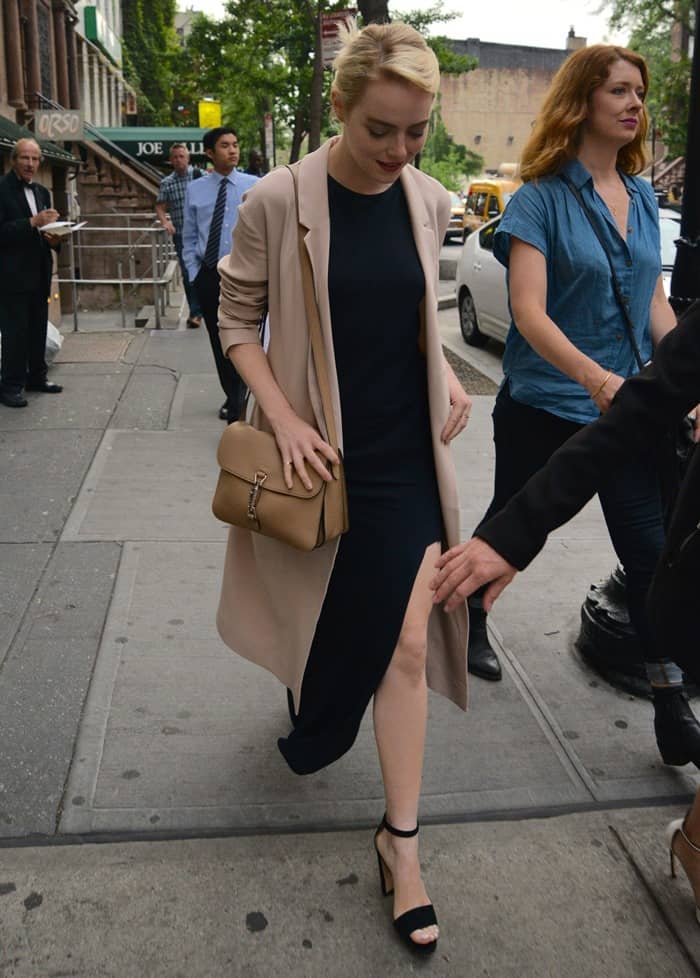 Emma Stone flaunts her legs in an ankle-length, navy dress styled with a Cos coat