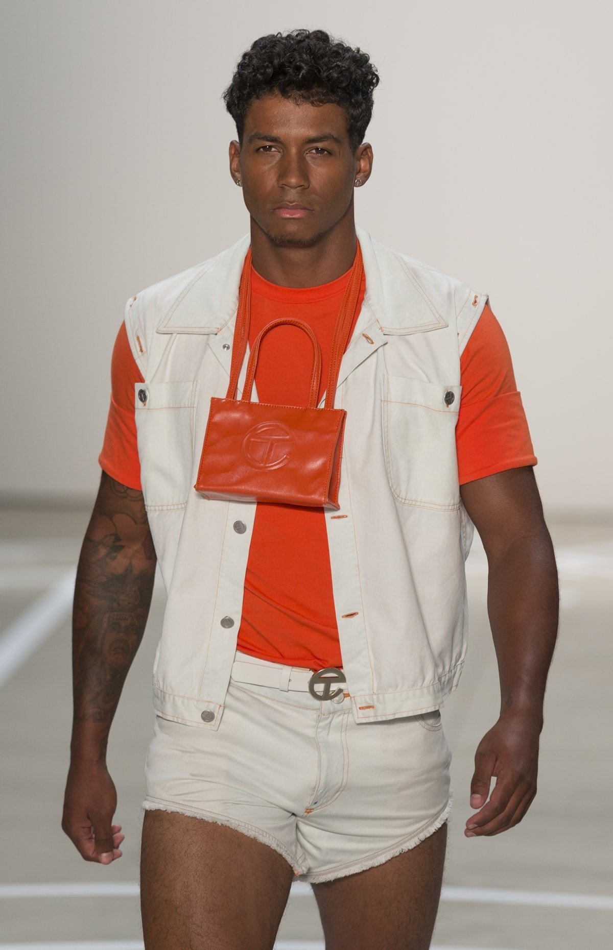 A male model walks the runway for Telfar by Telfar Clemens with a T logo shopping bag
